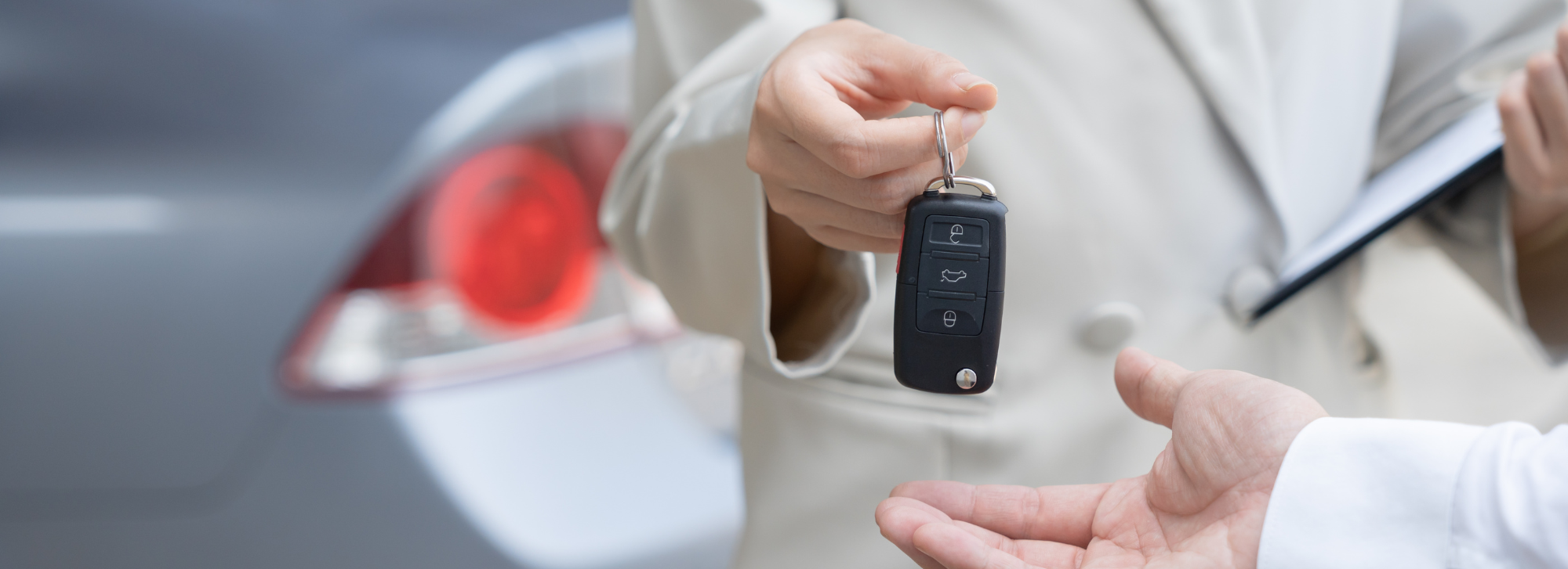 Person handing car keys to someone else.