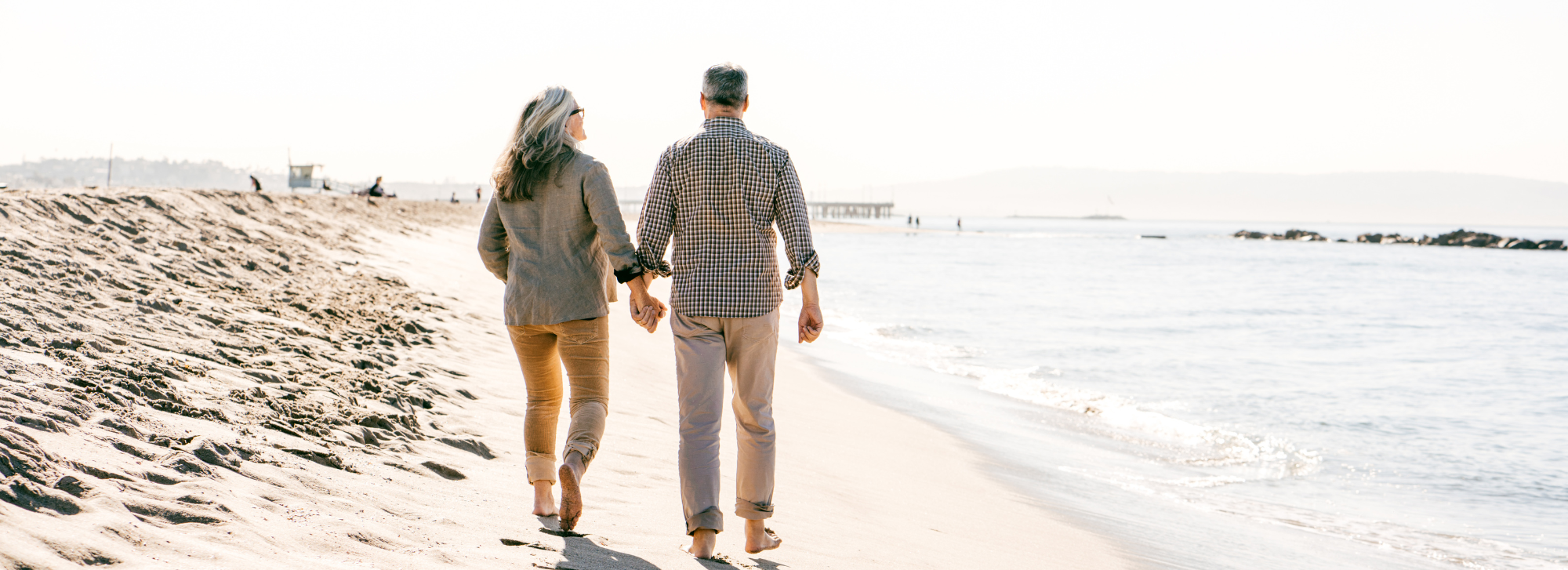 A couple walking on the beach on a sunny day.