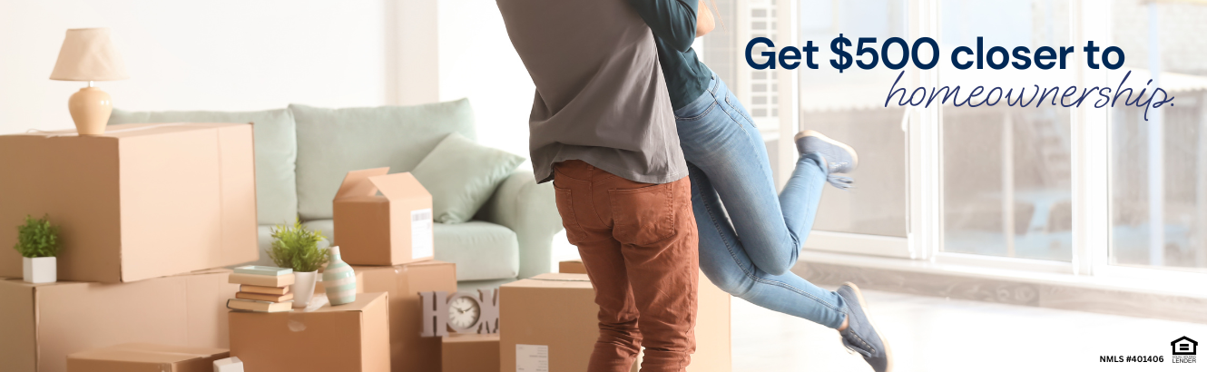 Man and a woman hugging in a living room surrounded by moving boxes.