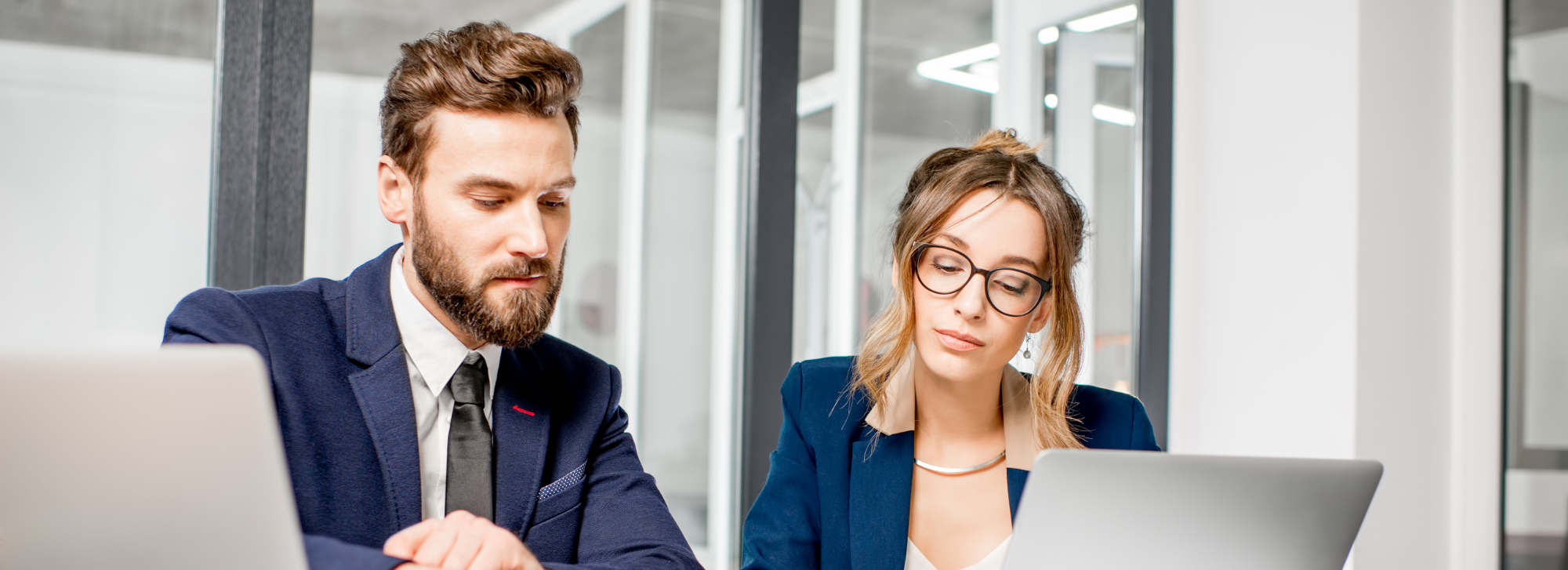 Two people sitting at computers working on something.